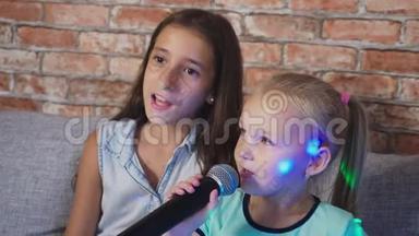 两个小女孩正对着麦克风唱歌。 家里卡拉OK里的歌。 4k，慢镜头，特写